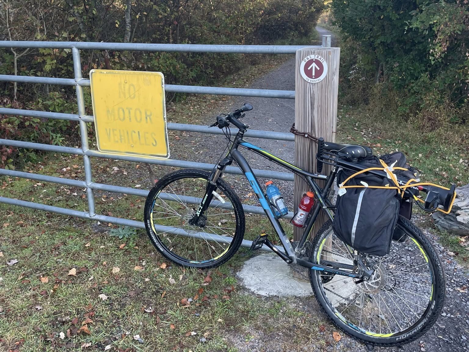 A bike laying against a fence post with a D&L Trail Marker