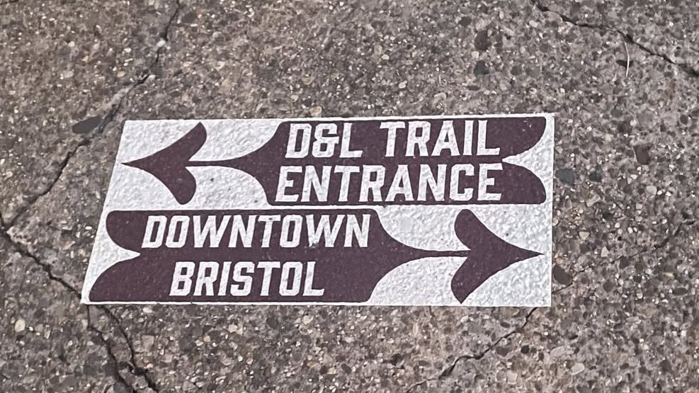 D&L Trail signage pointing left to the trail entrance, and right towards Downtown Bristol