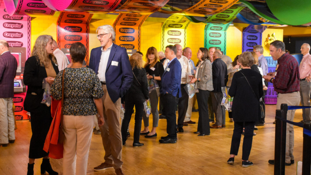 A large group of people mingling in front of a colorful exhibit at the Crayola Experience in Easton