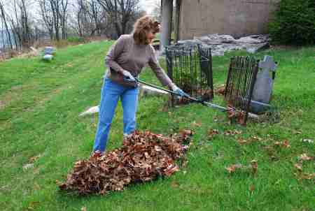 Jeanne Remmell rakes leaves to clear gravestones. (Photo Courtesy of Dana Grubb) 